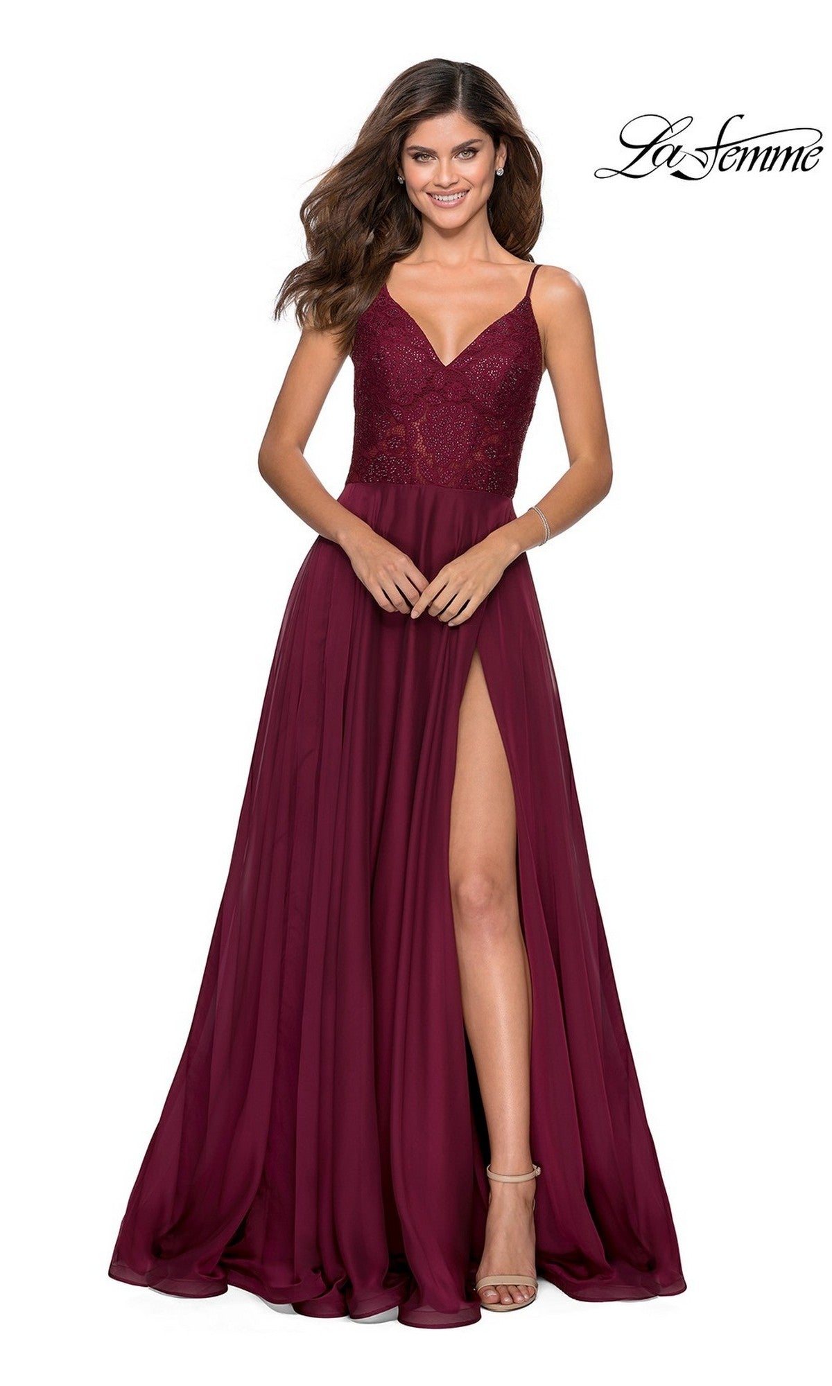 A woman in a wine La Femme Sheer-Lace-Bodice Long Prom Dress 28664, featuring a sheer embroidered bodice and high slit, stands and smiles against a white background.